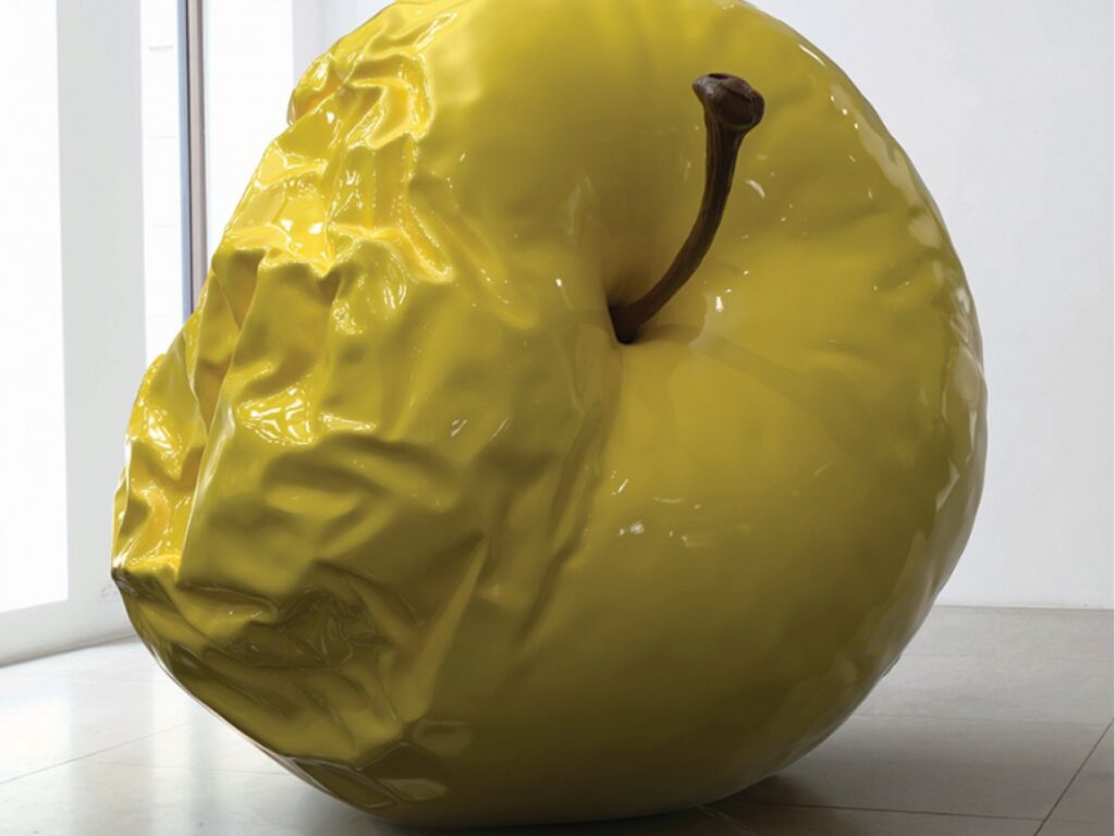 Żółta rzeźba „Giant Apple” Barnaby’ego Barforda eksponowana w David Gill Gallery w Londynie.