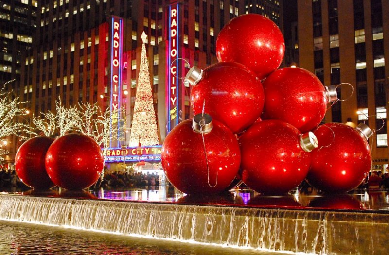 Gigantyczne czerwone bombki ustawione przy fontannie miejskiej w scenerii nocnej.