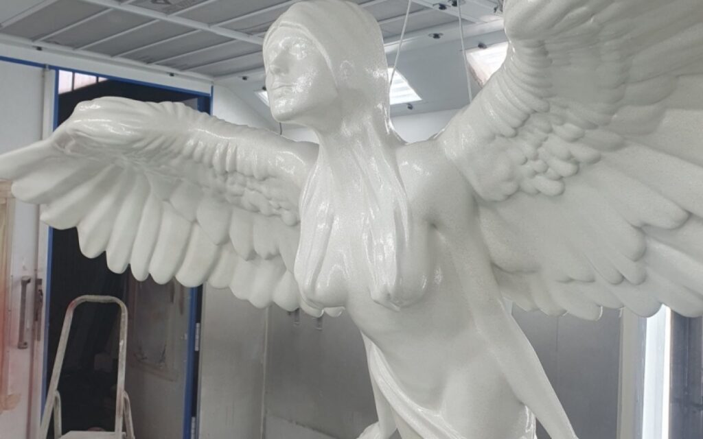Wielkogabarytowa biała rzeźba anioła z włókna szklanego w trakcie finalnego lakierowania w pracowni Malpol.