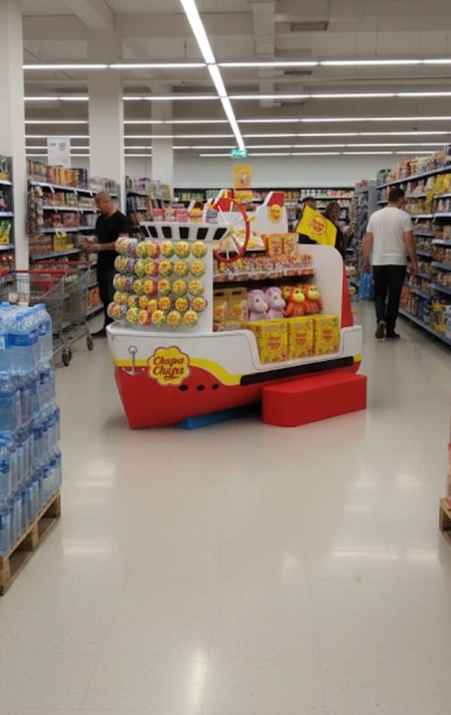 Kolorowy ekspozytor reklamowy Chupa Chups w kształcie łodzi, statek z fiberglass z półkami na lizaki i słodycze – stand POS 3D w sklepie spożywczym