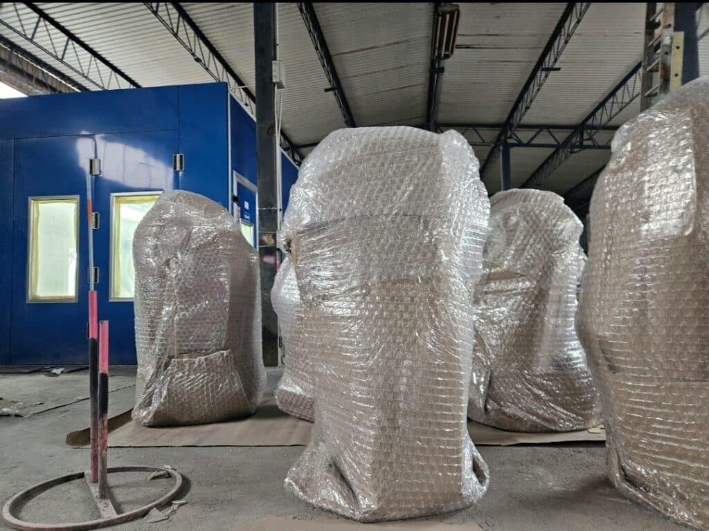 Zafoliowane, wielkogabarytowe figury i rzeźby 3D stojące na hali produkcyjnej, przygotowane do wysyłki i transportu.